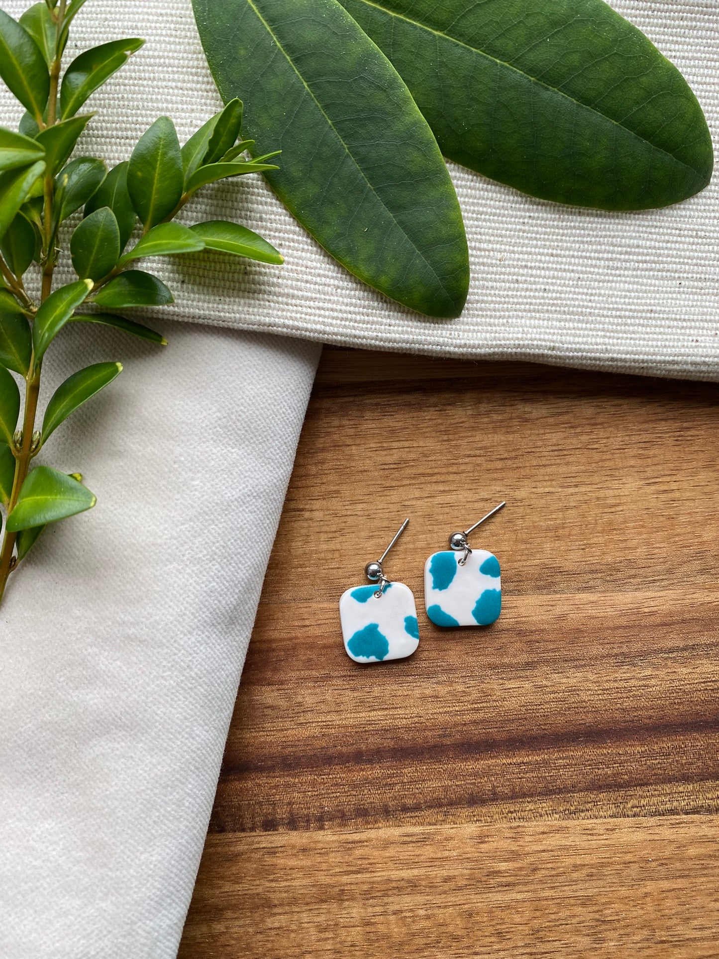 Dinky dangles - white and teal cow print squares